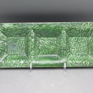 May include: A rectangular green ceramic serving tray featuring a three-section divided interior. The surface is decorated with a raised, repeating leaf pattern throughout, finished with a glossy glaze that highlights the texture of the foliage.
