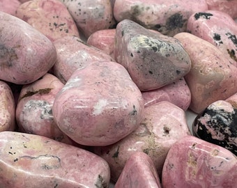 May include: A collection of pink and black tumbled stones. The stones are smooth and polished, with a variety of patterns and textures.