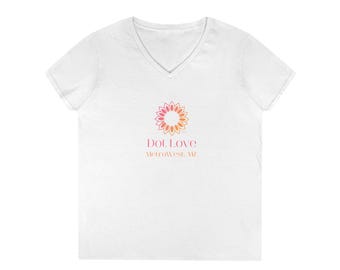 May include: A white V-neck t-shirt featuring a central graphic of a stylized flower with orange and pink petals. Below the flower, the text reads Dot Love in pink and MetroWest, AZ in orange. The shirt has short sleeves and a simple hem.