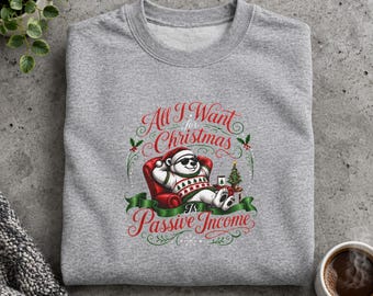 May include: A heather gray crewneck sweatshirt featuring a graphic of a polar bear wearing sunglasses and a patterned sweater, lounging in a red armchair. The text reads All I Want for Christmas Is Passive Income, surrounded by festive greenery.