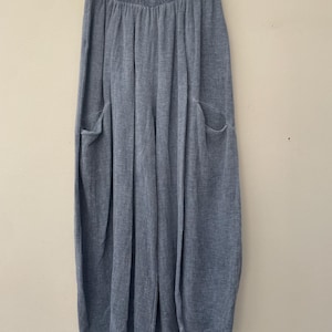 May include: Light blue wide-leg trousers with two large front pockets, hanging from a white hanger. The trousers have a soft, textured look and a relaxed fit, suitable for casual wear.