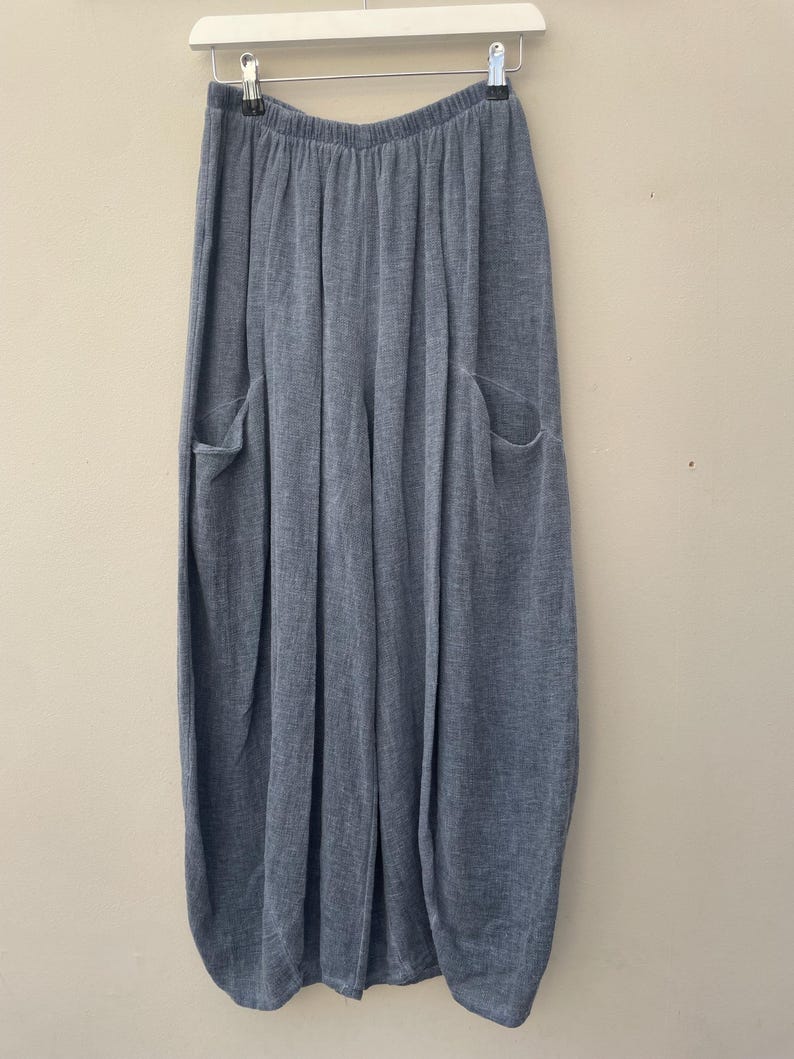 May include: Light blue wide-leg trousers with two large front pockets, hanging from a white hanger. The trousers have a soft, textured look and a relaxed fit, suitable for casual wear.