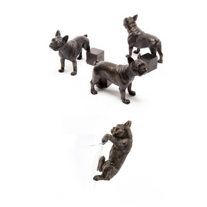 May include: Four bronze figurines of French Bulldogs, three standing on small black bases and one hanging from a glass object.