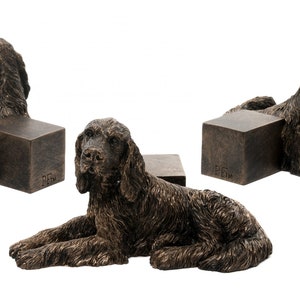 May include: Set of three bronze dog bookends featuring a reclining Cocker Spaniel. Each bookend is approximately 6 inches tall and 4 inches wide.