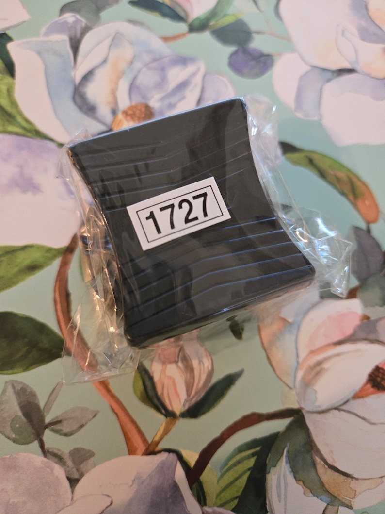 K&ouml;nnte beinhalten: Ein schwarzes Plastikobjekt mit einem Etikett, auf dem "1727" steht. Das Objekt ist in durchsichtige Plastikfolie verpackt.
