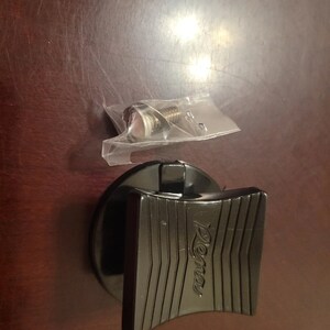 May include: Black plastic lid with a black lever and the word "Rema" embossed on it. A small plastic bag containing a screw is also visible.