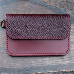 Cartera corta estilo camionero en piel Buttero lisa y escocesa color burdeos, con anilla de cadena. Billetera con cierre de cremallera para billetes, tarjetas y monedas. Hecha a mano en el Reino Unido.