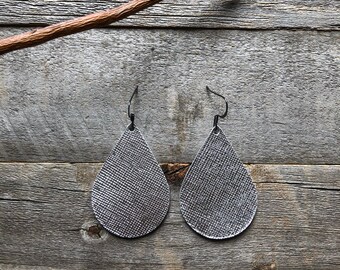 May include: A pair of silver teardrop-shaped earrings with a textured surface.