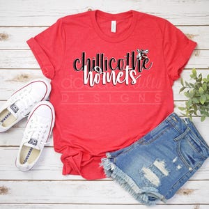 Könnte beinhalten: Rotes T-Shirt mit dem Text "Chillicothe Hornets" in Schwarz und Weiß. Eine schwarz-weiße Wespengrafik befindet sich über dem Text.