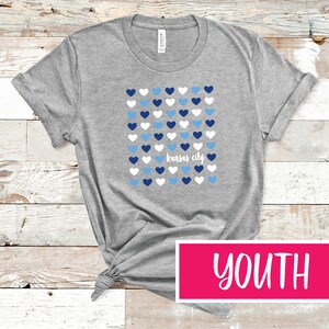 May include: Gray youth t-shirt with a pattern of blue and white hearts and the text "Kansas City".
