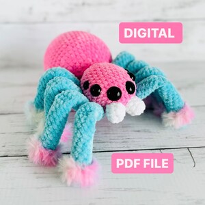 May include: A crochet amigurumi spider pattern in PDF format. The spider is pink with blue and white legs and has large black eyes.