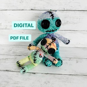 May include: Two crocheted voodoo dolls, one larger than the other, with colorful patchwork fabric and black buttons for eyes. The larger doll has pins stuck in it.  The dolls are sitting on a white wooden surface. DIGITAL PDF FILE.