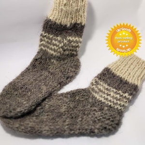 Può includere: Coppia di calzini in lana marrone e bianca con un motivo a righe. I calzini sono lavorati a maglia e hanno una texture soffice.