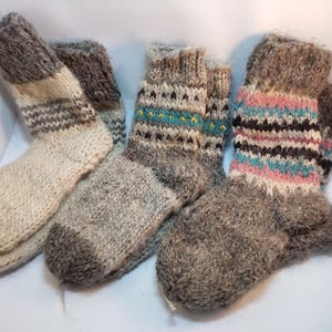 May include: Four pairs of wool socks with different patterns. The socks are grey, white and black with colourful stripes and designs.