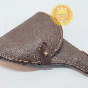 May include: A brown leather holster with a flap and a snap closure. The holster has a brown leather strap with a gold metal button.