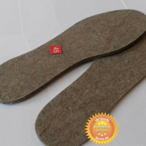 Puede incluir: Dos plantillas de fieltro marrón para zapatos, una con una etiqueta roja que dice "45".