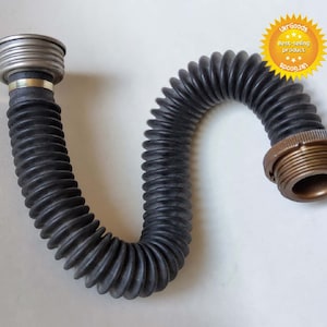 May include: A black rubber gas mask hose with a silver and gold metal connector on each end. The hose is flexible and has a corrugated design.