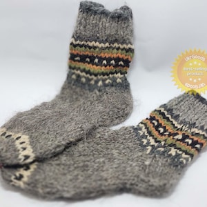 Puede incluir: Par de calcetines de lana grises con patrones geométricos coloridos. Los calcetines están hechos de lana gruesa y peluda y tienen un ajuste cómodo.