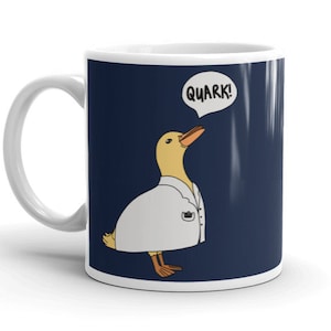 Könnte beinhalten: Eine weiße Keramiktasse mit blauem Hintergrund und einer Comic-Ente, die einen weißen Laborkittel trägt. Die Ente sagt "Quark!" in einer Sprechblase.