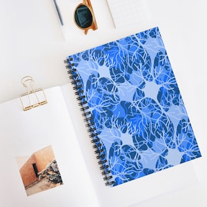 May include: Blue spiral notebook featuring a pattern of white neuron-like shapes on a light blue background.
