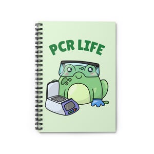 Könnte beinhalten: Spiralgebundenes Notizbuch mit hellgrünem Einband. Es zeigt einen Cartoon-Frosch mit Schutzbrille und blauem Handschuh neben einer PCR-Maschine. Die Worte "PCR LIFE" sind grün über dem Frosch gedruckt.