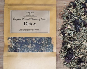 May include: A brown paper bag with a label that reads "Muddy Boots Herbal Teas Organic Herbal Cleansing Tonic Detox" and lists the ingredients: Nettle, Hibiscus, Burdock Root, Ginger Root, Rosehip, Marshmallow, Sage, Dandelion, Mullrin. The bag contains a loose blend of dried herbs.