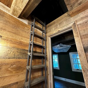 Large attic ladder with custom dark brown stained wooden treads placed in a residential laundry room