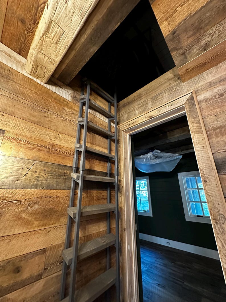 Large attic ladder with custom dark brown stained wooden treads placed in a residential laundry room