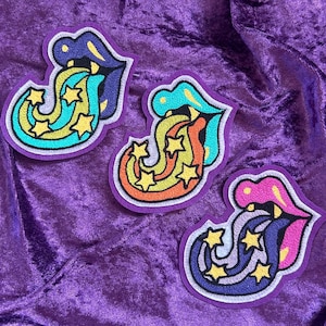 May include: Three embroidered iron-on patches featuring a tongue with a rainbow and stars coming out of the mouth. The tongues are blue, orange, and purple.