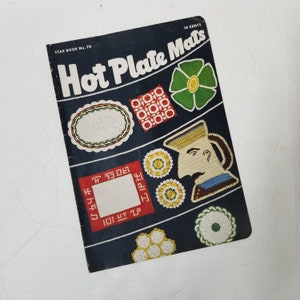May include: Vintage "Hot Plate Mats" booklet with a dark blue cover. The cover features various colorful crochet designs, including floral and geometric patterns. Text on the cover reads "Hot Plate Mats" and "10 Cents".