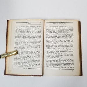 Puede incluir: Un libro abierto con texto en p&aacute;ginas envejecidas, con un bol&iacute;grafo dorado en el lado izquierdo. La portada del libro es de color marr&oacute;n oscuro y las p&aacute;ginas est&aacute;n amarillentas.