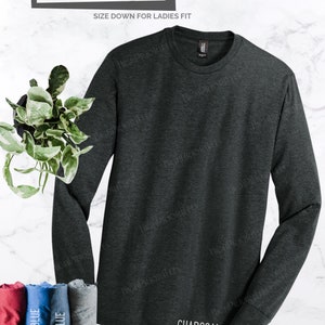 May include: A charcoal gray long-sleeve t-shirt with a relaxed fit. The shirt is made of a soft, comfortable material and is perfect for everyday wear.  "LONG SLEEVE" and "UNISEX RELAXED FIT" are printed on the top of the shirt.  "SIZE DOWN FOR LADIES FIT" is printed below the text.  "CHARCOAL" is printed on the bottom of the shirt.  "OTHER COLORS UPON REQUEST ~MESSAGE ME" is printed below the word "CHARCOAL".