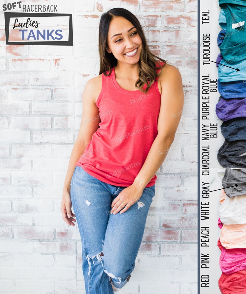May include: A woman wearing a red racerback tank top and blue jeans. The tank top is part of a collection of racerback tank tops in various colors, including pink, peach, white, gray, charcoal, navy, purple, royal blue, turquoise, and teal.