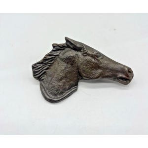May include: A bronze-colored cast iron horse head sculpture. The horse head is in profile, with detailed features including the mane, eye, and muzzle. The sculpture is likely a decorative item, possibly for a wall or door.