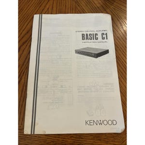 May include: A white instruction manual for a Kenwood Stereo Control Amplifier Basic C1. The cover features the product name, a black and white illustration of the amplifier, and the Kenwood logo at the bottom, with black text on a white background.