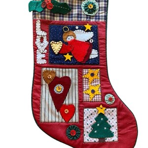 May include: Red Christmas stocking with various fabric appliqués. Features a plaid top, the word "LOVE", an angel, hearts, stars, and a Christmas tree. Decorative buttons and a green holly accent complete the design. A festive holiday decoration.