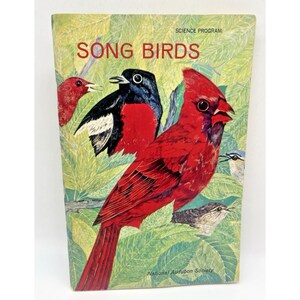 May include: A vintage book cover titled "SONG BIRDS" from the Science Program series. The cover features illustrations of various colorful birds, including a vibrant red cardinal and a black and red bird, set against a backdrop of green leaves.