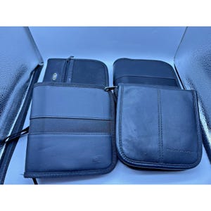 May include: An assortment of black CD/DVD cases. The cases are made of various materials, including leather and fabric, and feature zippered closures. Some cases have a handle or strap for carrying.