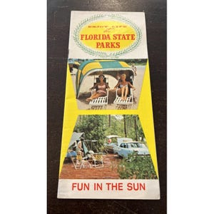May include: Vintage Florida State Parks brochure. The cover features the text "Enjoy Life at Florida State Parks" in a circular design. The brochure shows two women relaxing on beach chairs under a striped canopy. The bottom section shows a camping scene with a vintage car.