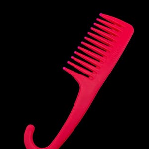 May include: A bright pink plastic comb with a handle that curves into a hook shape.