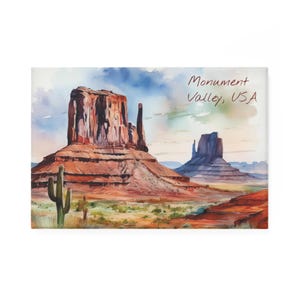 May include: A watercolour painting of Monument Valley, USA. The image shows the famous sandstone buttes in shades of red and brown under a blue sky. A cactus is in the foreground, with the text "Monument Valley, USA".