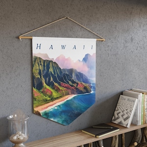 Può includere: Un banner da parete con una vista panoramica delle Hawaii. Il banner mostra un paesaggio costiero con montagne verdi, una spiaggia sabbiosa e acque blu dell'oceano. La parola "HAWAII" è stampata in alto in lettere blu navy. È sospeso da un'asta di legno.