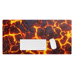 May include: A desk mat with a fiery orange and red lava flow design. A white keyboard and mouse are placed on the mat.