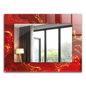 May include: A rectangular mirror with a red and gold abstract design frame. The mirror reflects a room with a window and curtains.