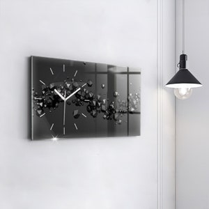 Peut inclure: Une horloge noire et blanche avec un design géométrique. L'horloge est en verre et a un cadran blanc avec des aiguilles noires. L'horloge est accrochée à un mur blanc.