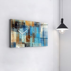 Puede incluir: Un reloj abstracto moderno con un diseño azul, marrón y blanco. El reloj tiene una esfera blanca con agujas negras.