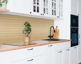 May include: A white kitchen with white cabinets, a black faucet, a black sink, and a black oven. There is a small plant in a wicker pot on the counter. The backsplash is a light brown wood.