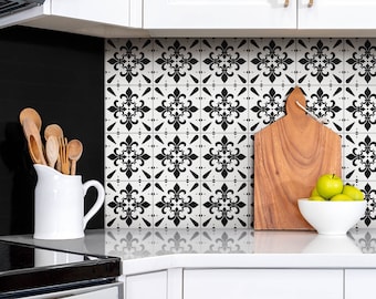 May include: Black and white patterned tile backsplash in a kitchen with a white countertop, a wooden cutting board, and a bowl of green apples.