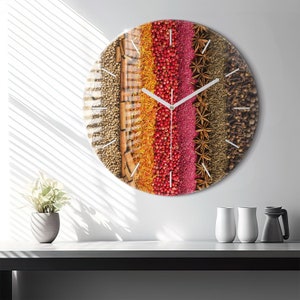 Könnte beinhalten: Eine runde Uhr mit weißem Zifferblatt und schwarzen Zeigern. Das Zifferblatt der Uhr ist mit einer Collage aus verschiedenen Gewürzen bedeckt, darunter Zimtstangen, Sternanis, Pfefferkörner und getrocknete Kräuter.