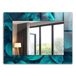 Puede incluir: Un espejo rectangular azul turquesa con un patrón de hojas alrededor del marco. El espejo refleja una habitación con una ventana y una lámpara.